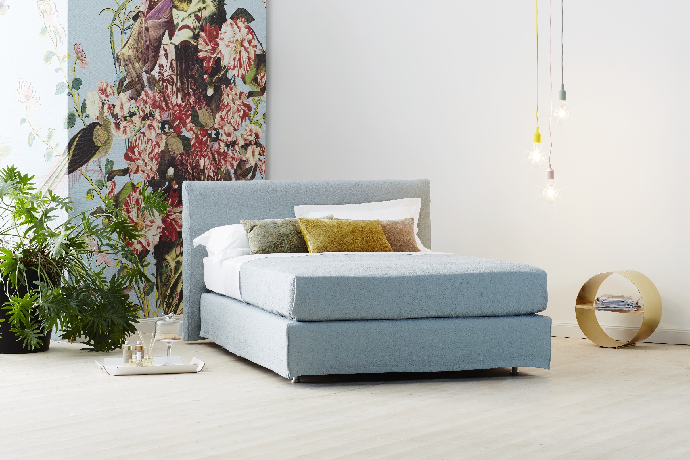 Schramm Boxspring Bett in stahblau im Hintergrund mit blumiger Tapete