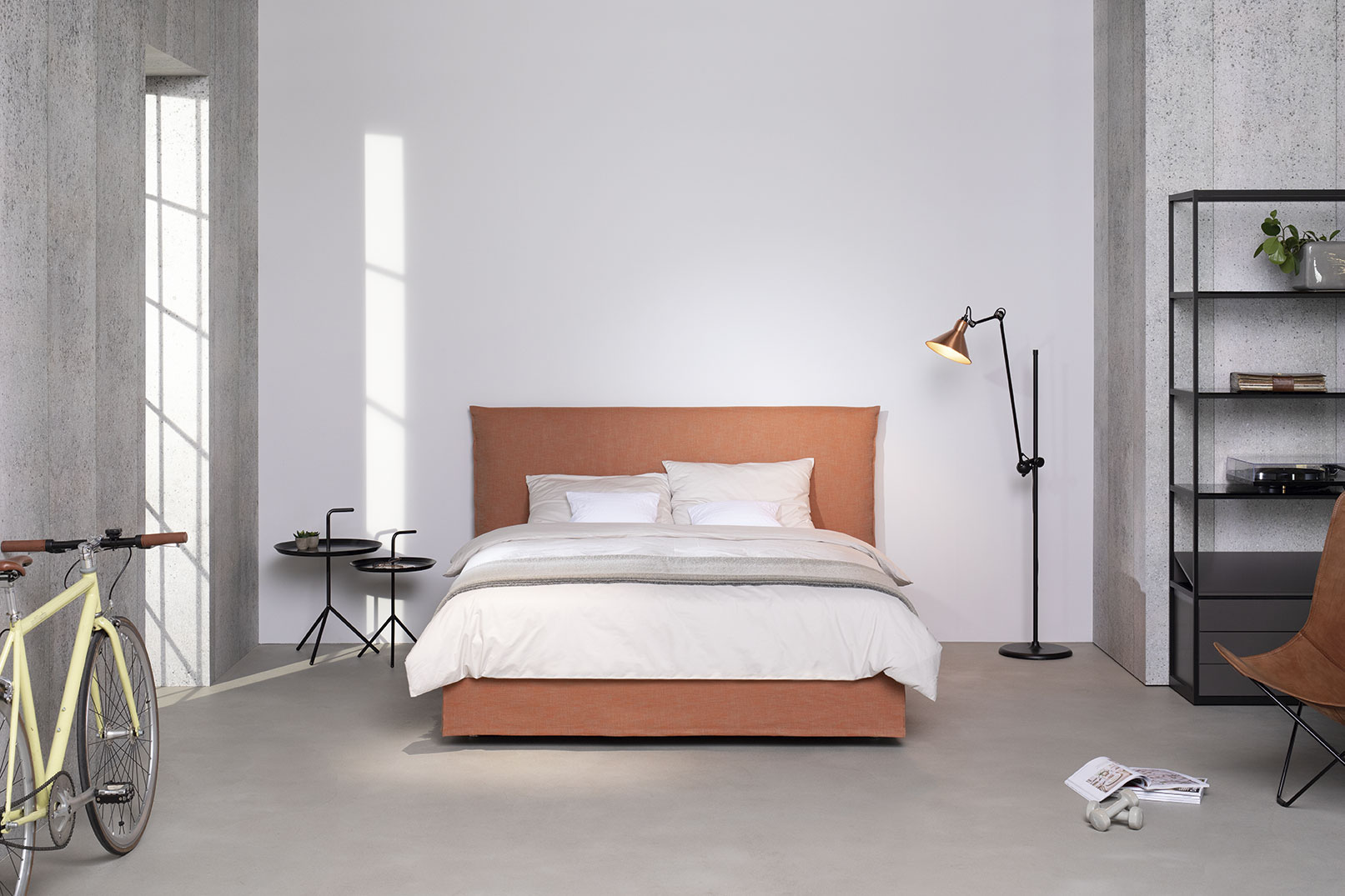 Schramm Boxspring Bett in apricot im Hintergrund mit weisser wand